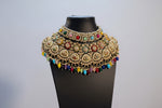 Ornate gold necklace and earrings with colorful beads on a mannequin bust.