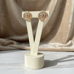 ALT Text: A pair of golden wheel-shaped stud earrings intricately detailed with sparkling clear CZ stones.