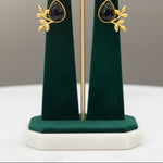 A Close-up of a woman wearing studs a black stone and gold earring 