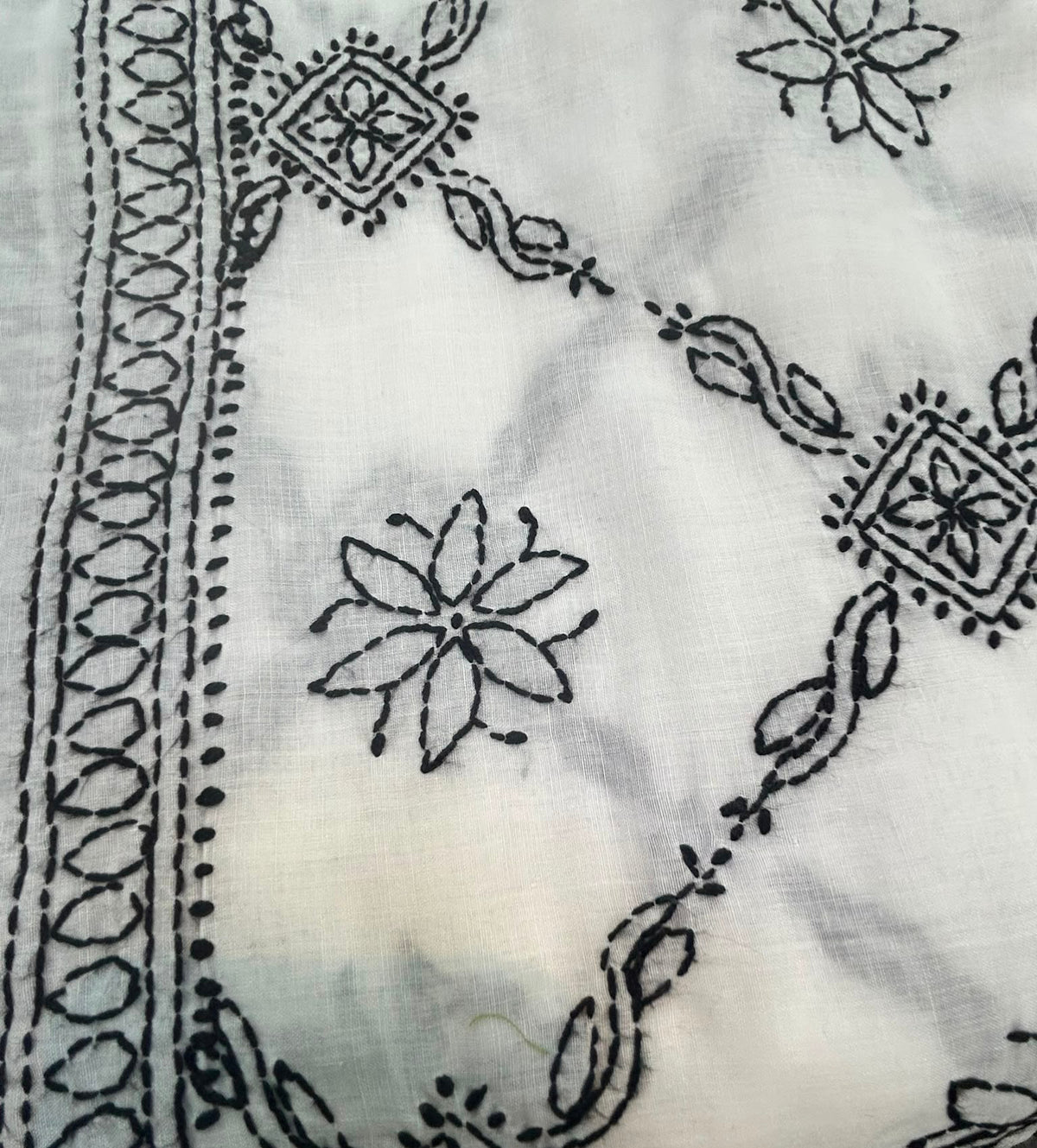 A Close-up of black embroidered patterns on a white fabric.