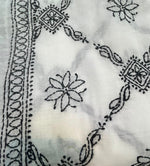 A Close-up of black embroidered patterns on a white fabric.