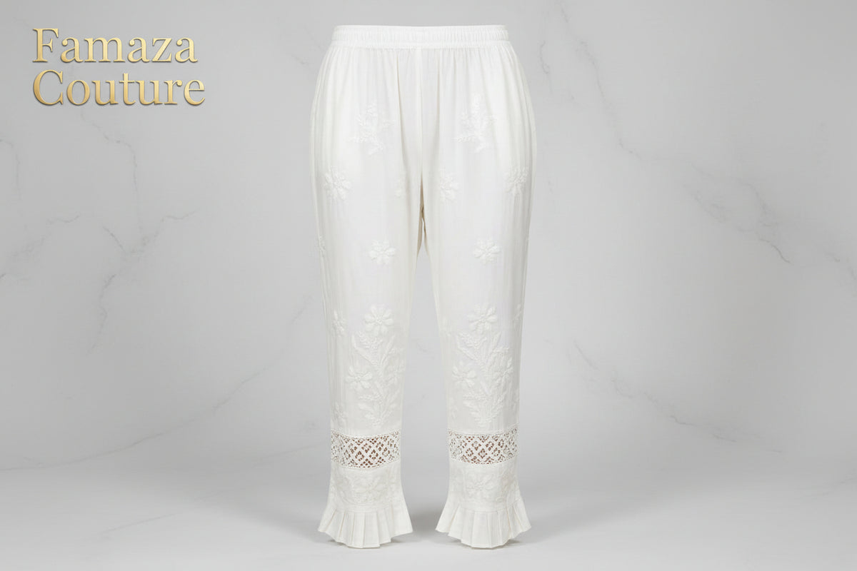 A Close-up of white embroidered cotton pants with pockets, showing the texture and design details. 