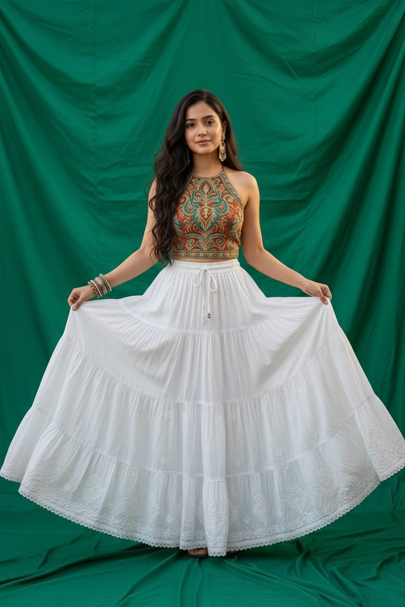 A Model is wearing the white rayon skirt with white Ghasspati hand embroidery on the bottom two layers and the hem is adorned with white crochet lace. 