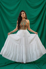 A Model is wearing the white rayon skirt with white Ghasspati hand embroidery on the bottom two layers and the hem is adorned with white crochet lace. 