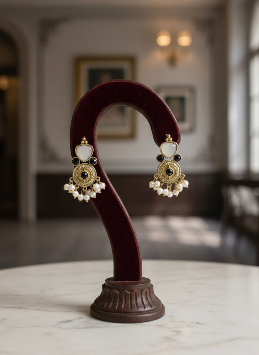 Pair of gold and white earrings with 3 tiny black stones and nano pearls hangings in the bottom.