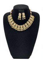 Gold necklace and earrings set on a black bust