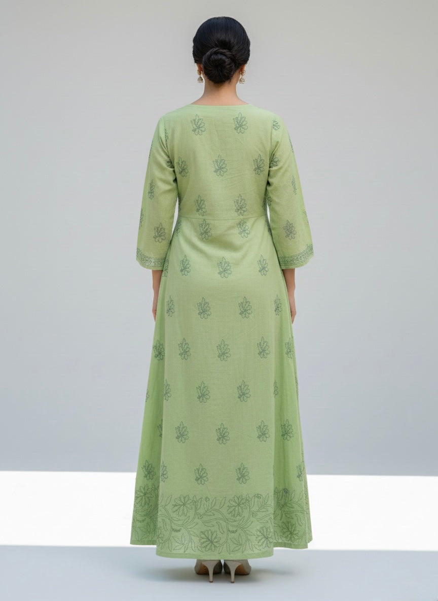 A apple green dress with floral patterns on a grey surface with small decorative items.