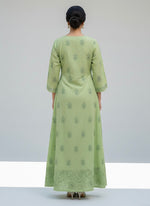 A apple green dress with floral patterns on a grey surface with small decorative items.