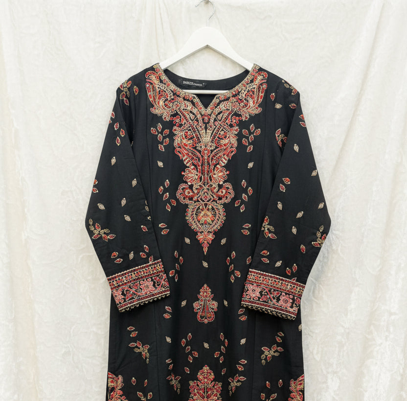 A black long-sleeve kurta with intricate red, gold, and beige embroidery concentrated on the yoke and cuffs, laid flat on a patterned fabric surface.