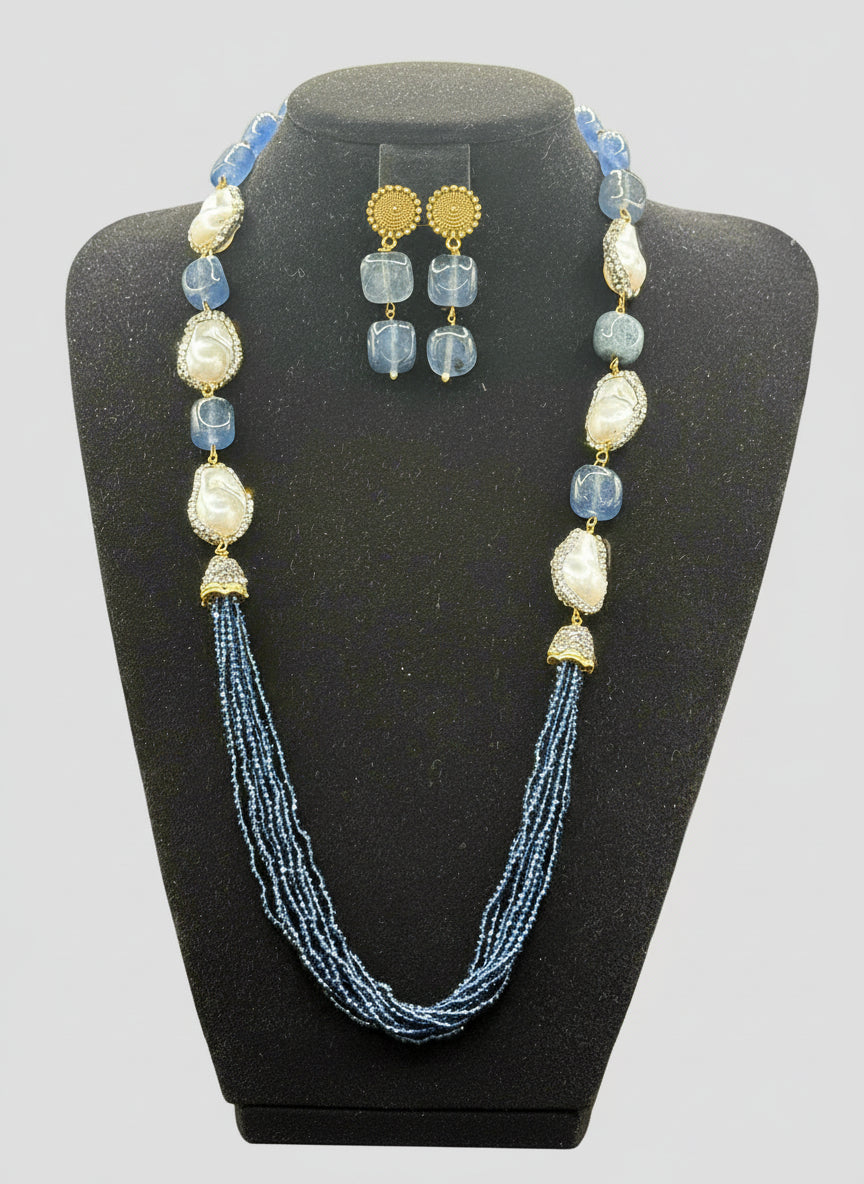 A black mannequin showcasing a Bollywood style Navy blue colour Mona Lisa stone and Navyblue colour nano crystal beaded Mala set, with white colours of baroque pearls and gold-tone accents. Party wear jewellery set. 