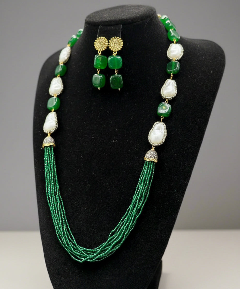 A black mannequin showcasing a Bollywood style bottle green Mona Lisa stone and bottle green nano crystal beaded Mala set, with white baroque beads and gold-tone accents. Party wear set. 