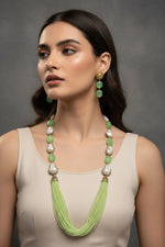 A black mannequin showcasing a Bollywood style lime green colour Mona Lisa stone and lime green colour nano crystal beaded Mala set, with white colours of baroque pearls and gold-tone accents. Party wear jewellery set. 