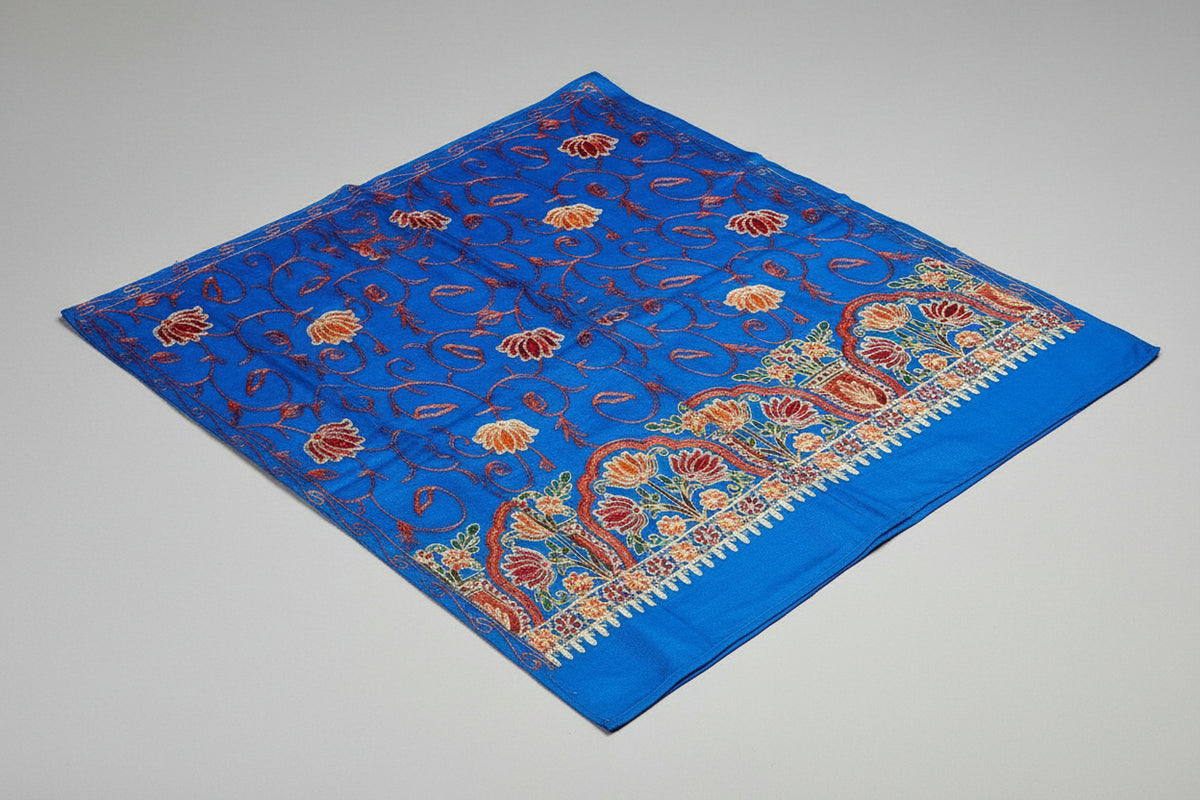A blue Kashmiri embroidered pashmina scarf with floral patterns and a geometric border in orange and red.