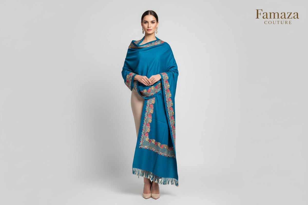 A blue pashmina scarf with rose and floral aari embroidery and tassels on the edges.