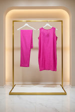 A bright magenta pink sleeveless tunic top with a matching straight trousers, displayed on a clothing rack in a Famaza Couture. 