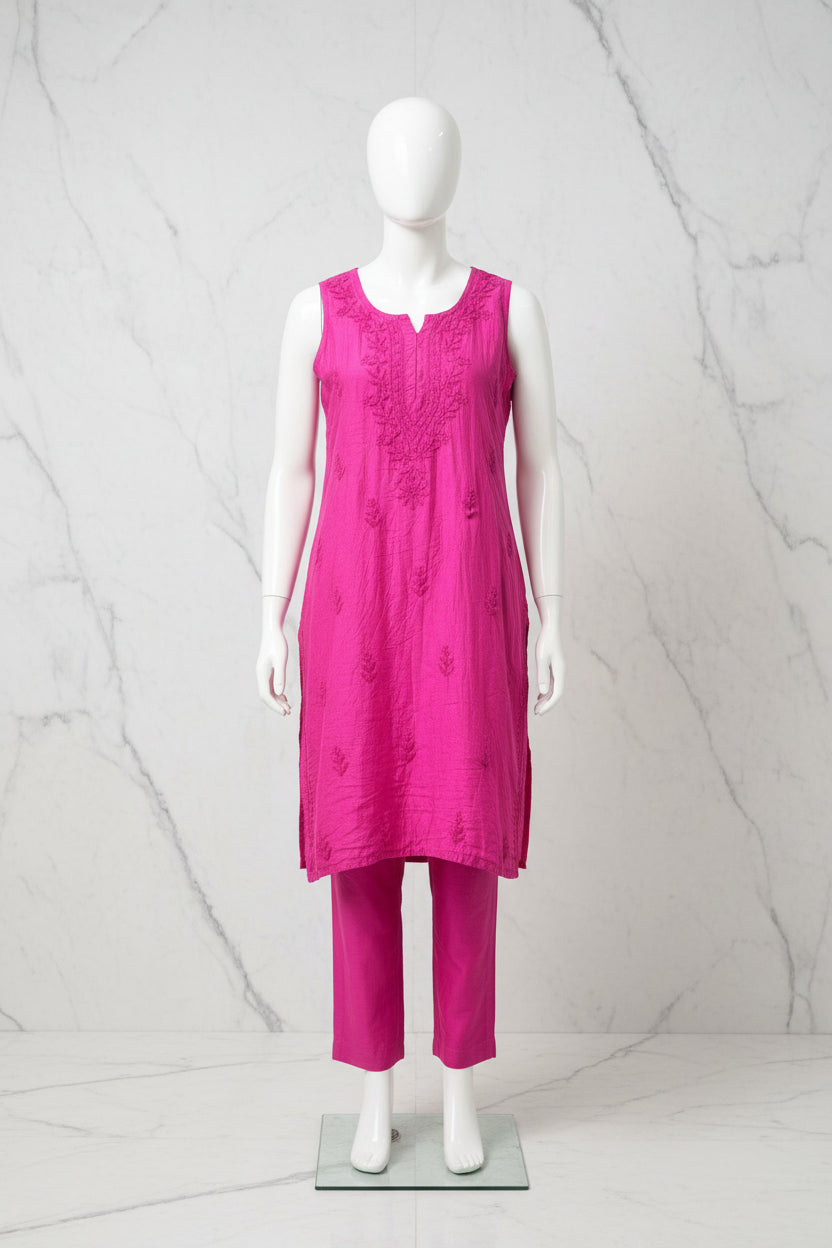 A bright pink chanderi fabric sleeveless embroidered kurta hanging on a white hanger with matching straight trousers displayed o