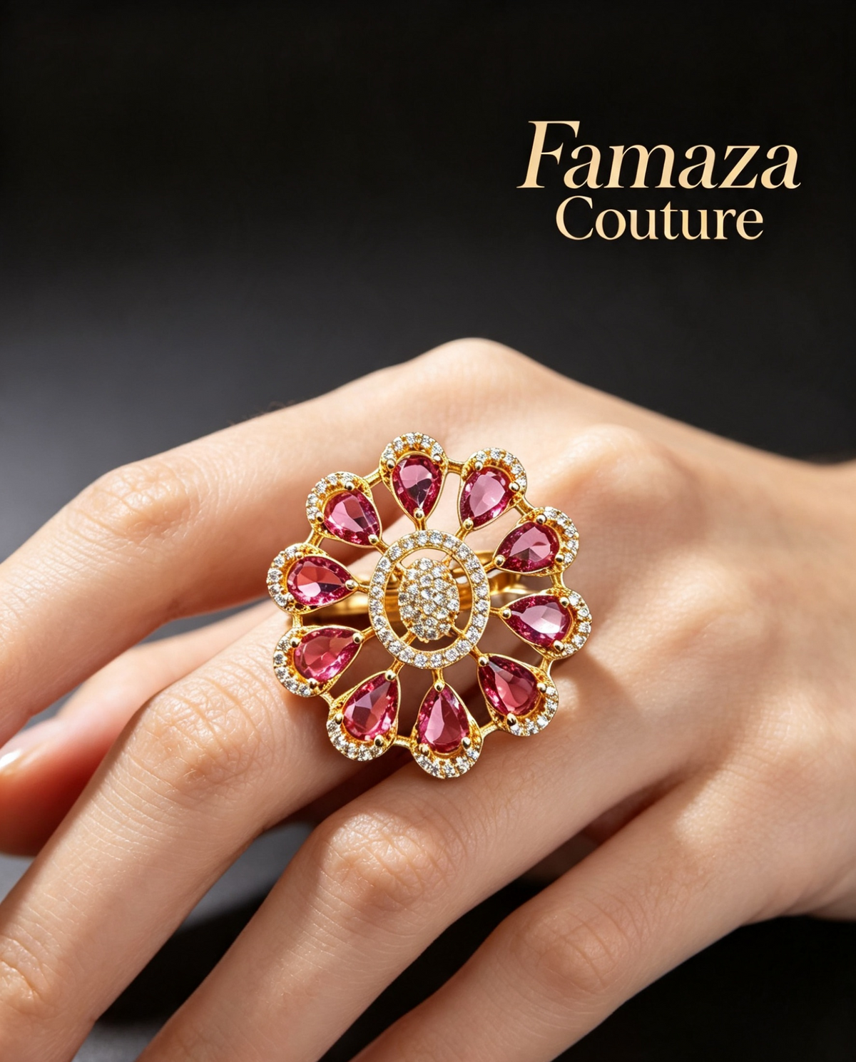 A close-up of a hand wearing a large floral-shaped ring by Famaza Couture. The ring features pink gemstones in teardrop shapes around a central clear stone, set in yellow gold with small clear accent stones.