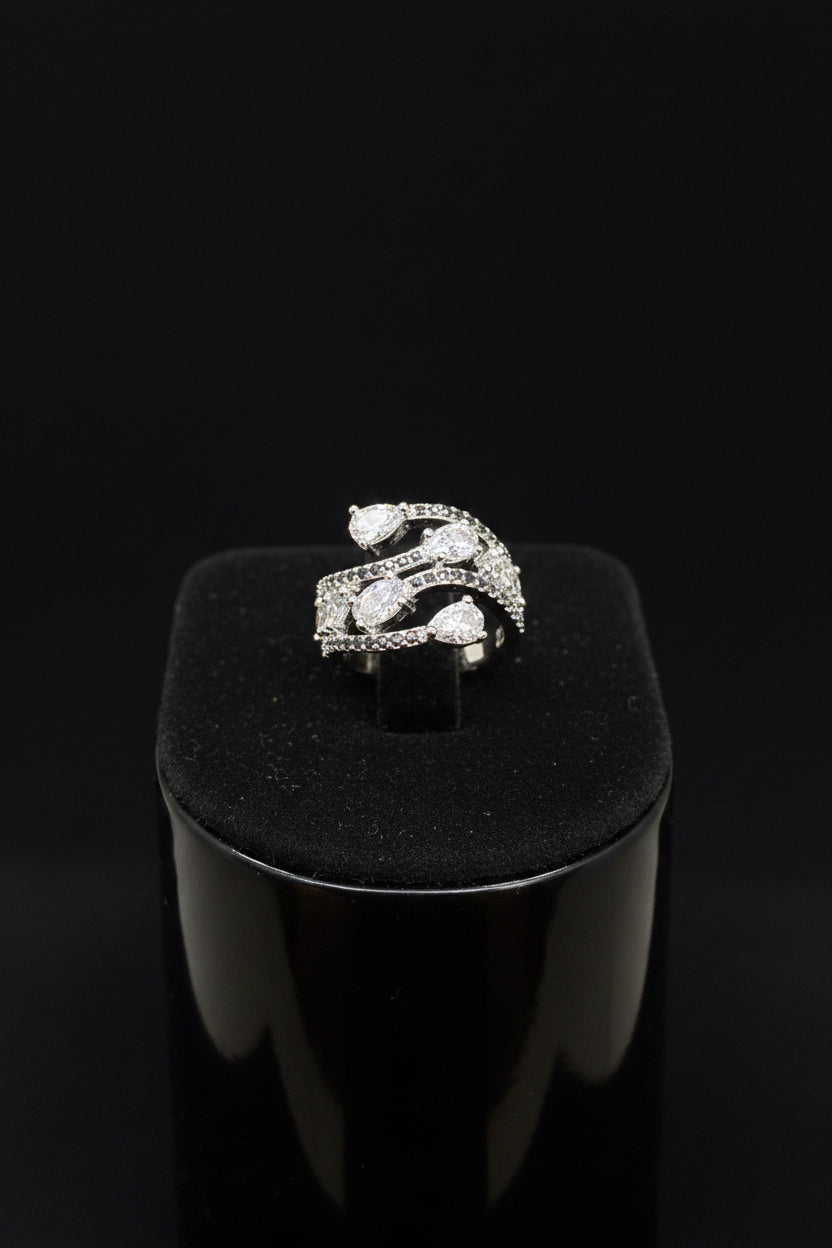 A close-up of a hand wearing a silver snake-themed ring set with clear pavé stones, shown against a black background.