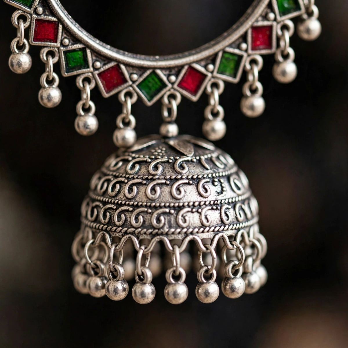 Close-up of the silver-tone jhumka dome with green and red enamel detailing and dangling beads.