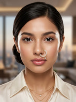 A close-up portrait of a woman wearing a gold crescent moon nose ring adorned with small white pearls, styled with layered gold necklaces and a cream-colored collared shirt.