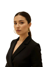 A elegant lifestyle shot of a woman wearing the 10ct gold-plated brass baali earrings, highlighting the classic hoop silhouette and the secure push-back closure against her jawline.