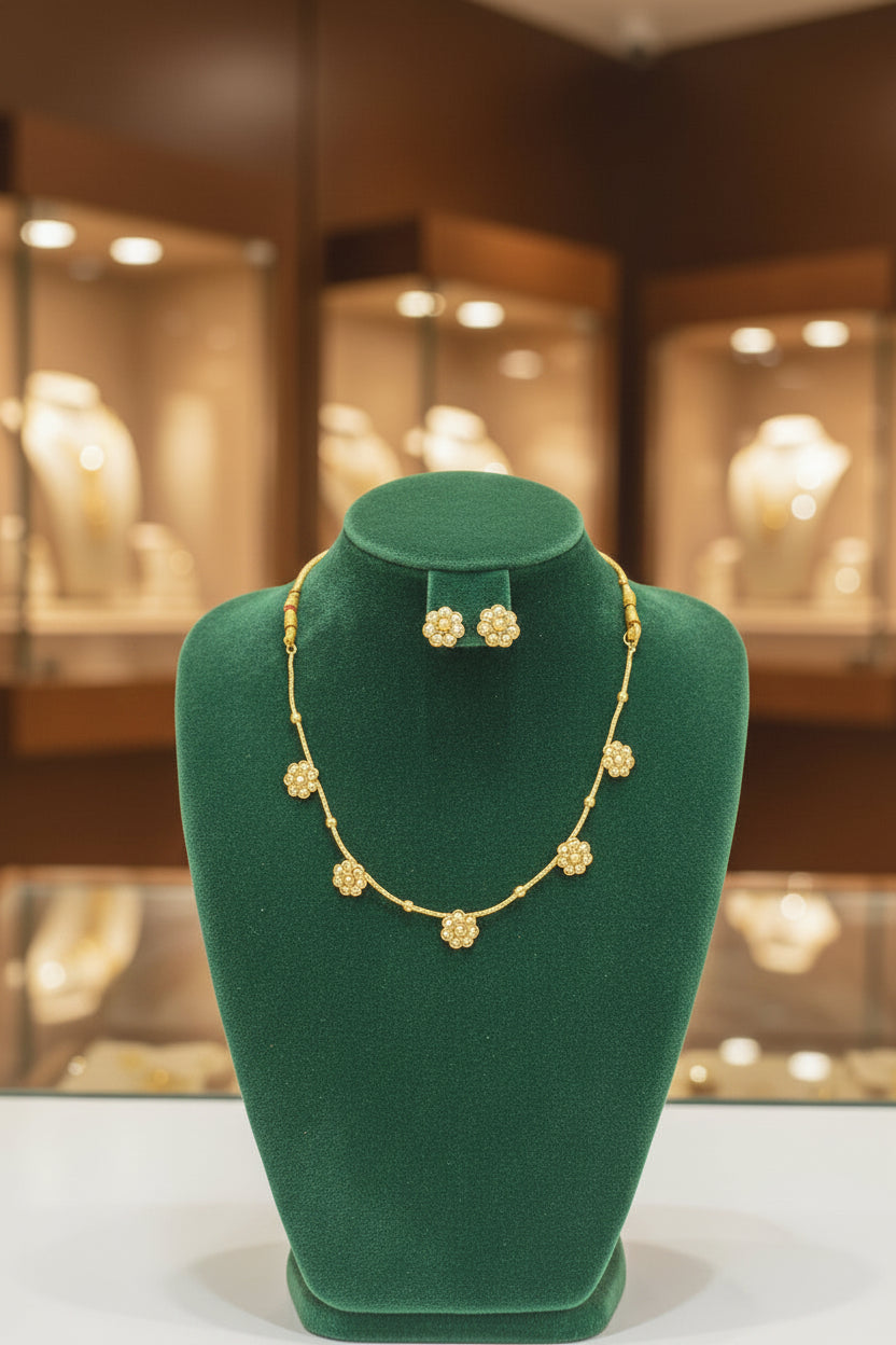 A fine gold-toned jewelry chain showing the spacing of the delicate pearl flower charms and the adjustable yellow thread closure.
