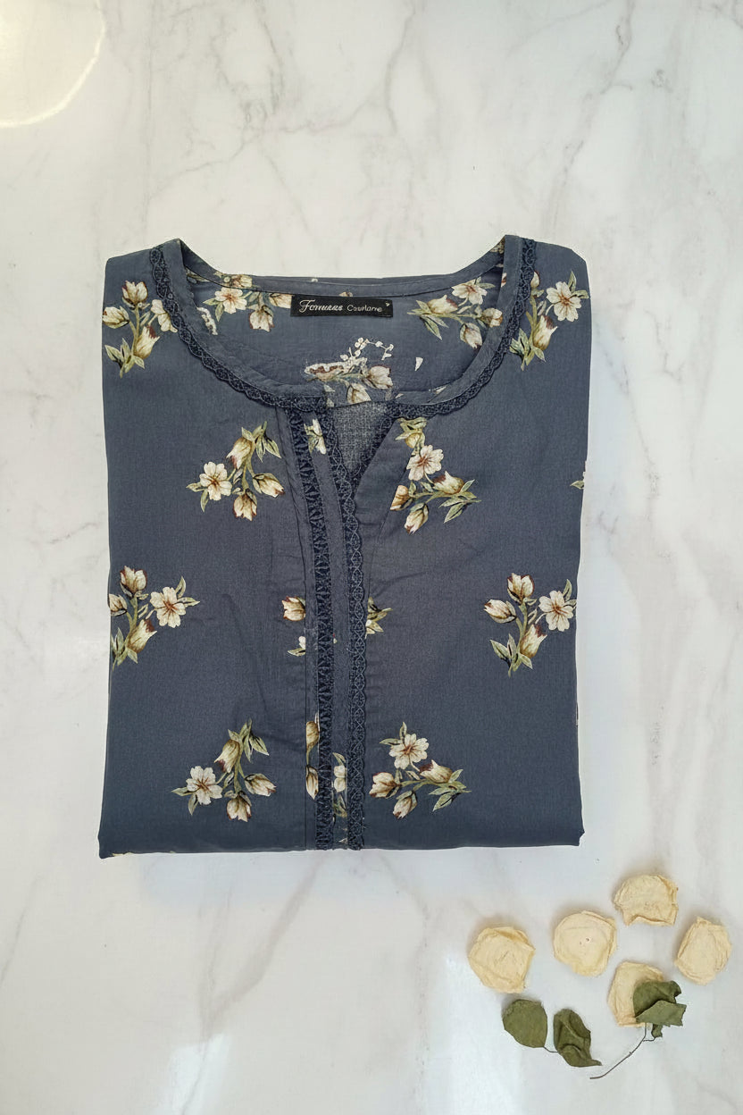 A folded slate blue kurta featuring a cream and green floral print, with a decorative lace trim along the neckline and chest. A black brand label reading Famaza Couture is visible on the inside collar.