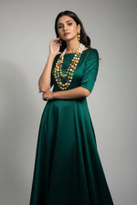 A gold-plated Kundan-studded and pearl-beaded handcrafted jewellery set, consisting of a necklace and earrings, displayed against a black background. Party wear 3 layered mala.