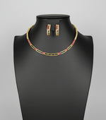 A gold-tone Hasli necklace set with American diamonds and semi precious ruby stones, displayed on a mannequin neck.