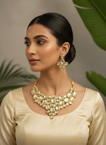A gold-toned Drop & Oval Kundan Necklace set with matching earrings displayed on a stand, featuring Polki Kundan craftsmanship and Meenakari detailing by famaza couture 