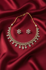 A gold and white jewellery set displayed on a black velvet mannequin bust, featuring a leaf-patterned choker necklace and matching Star of David earrings, with a hand holding the display stand in a retail store.