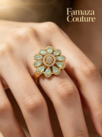 A gold flower-shaped ring with light green marquise-cut stones and a central round stone cluster, worn on a hand. The brand name 'Famaza Couture' is printed in gold text in the top right corner.