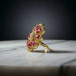 A gold ring with multiple red gemstones, photographed on a textured white faux fur surface.
