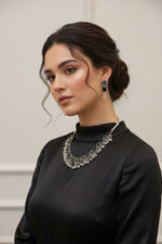 A model wearing a oxidised black stone necklace with matching floral earrings, showcasing the tribal silver aesthetic