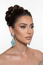 A model wearing radiant teal floral gala chandelier earrings.