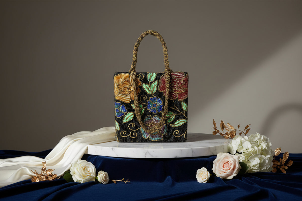A multi-coloured floral handcrafted tote bag with glass beads embroidered on it, displayed on a wooden surface.