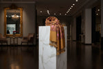 A mustard colour pashmina scarf with Kashmiri embroidery in a floral pattern, featuring tassels on the ends.