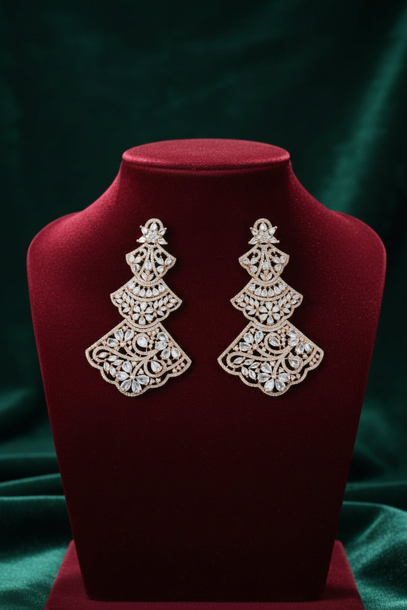 A pair of Rose gold-tone three-tiered chandelier earrings with intricate filigree lattice metalwork and sparkling cubic zirconia crystals, displayed on a red velvet jewellery bust.