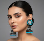 A pair of black Jhumki earrings with sunflower designs, featuring sky blue and silver multi shade stones and sky blue nano hangings.