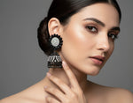 A pair of black base metal Jhumki earrings with sunflower designs, featuring black and silver multi shade stones and sky blue nano hangings.