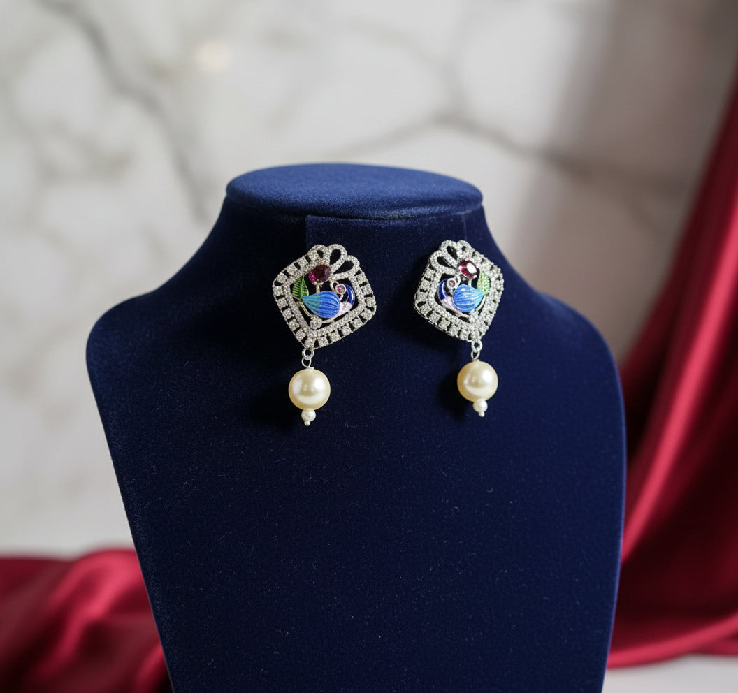 A pair of earrings of peacock-shaped earrings with blue, green, and gold enamel accents and white faux pearl. 