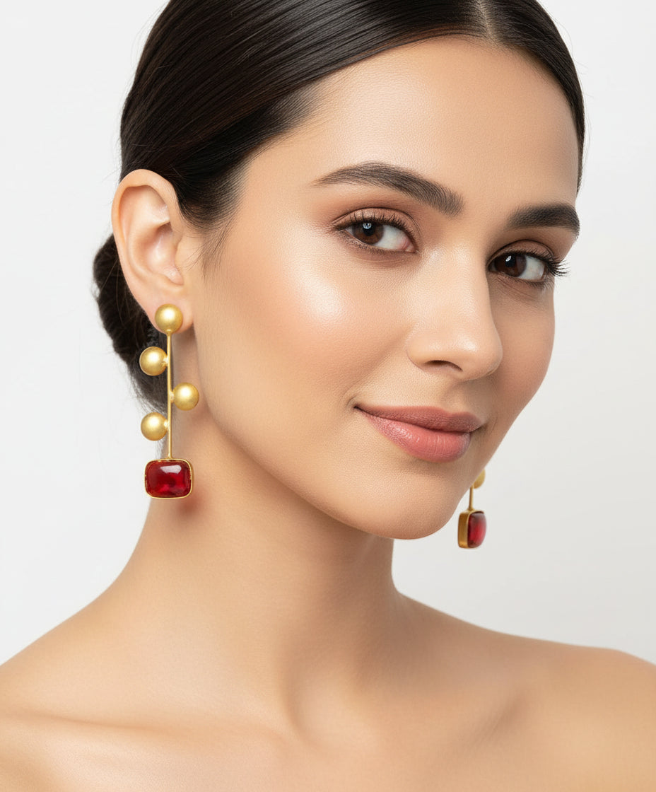 A pair of gold-plated Monalisa red stone earrings with golden coin details.