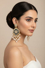 A pair of gold-plated Parul Pearl kundun earrings with intricate designs and drop-shaped pearls, displayed on a stand.