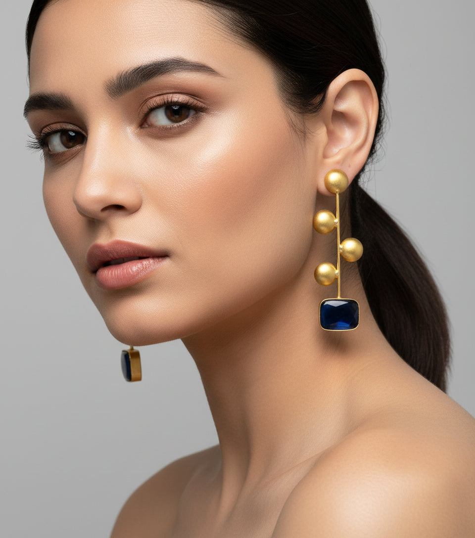 A pair of gold-plated earrings with navy blue Monalisa stone and coin details.