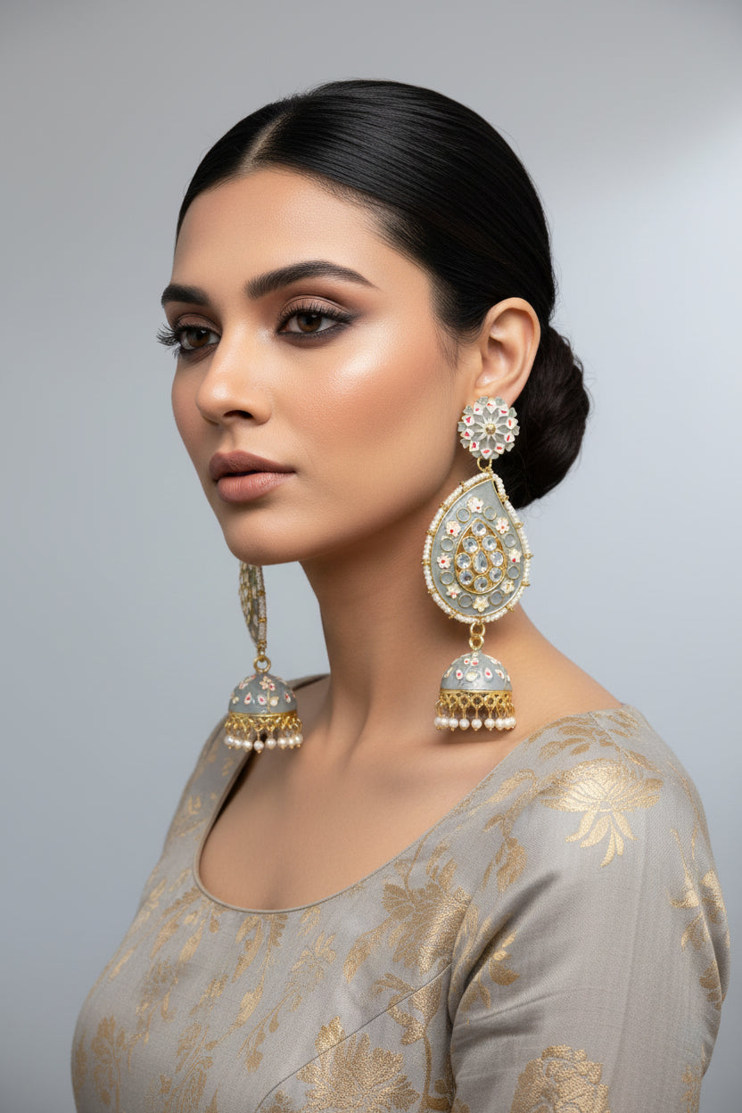 A pair of gold-plated grey Meenakari long Jhumka earrings with grey enamel paint and nano pearl drops, displayed on a stand.