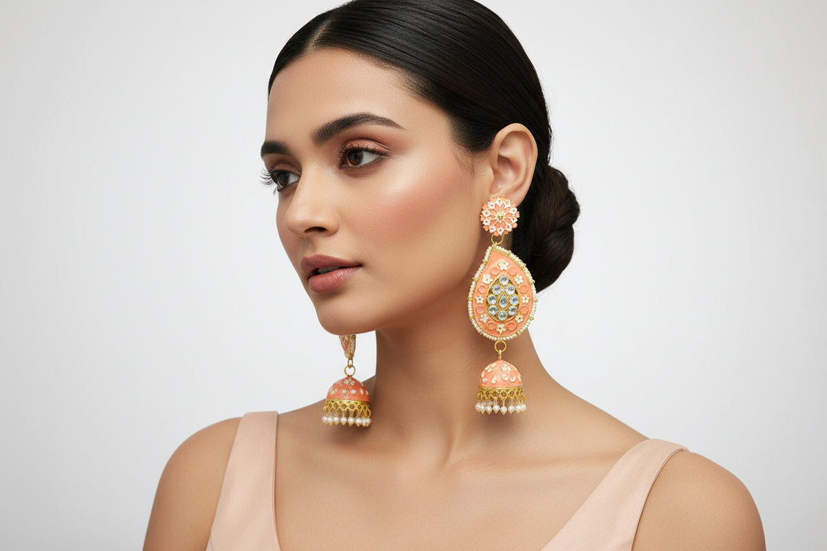A pair of gold-plated peach Meenakari long Jhumka earrings with peach enamel paint and nano pearl drops, displayed on a stand.