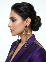 A pair of long gold-toned chain earrings featuring a red floral Kundan stud and white pearl border worn by a model.