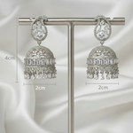 A pair of silver-toned jhumka earrings displayed on a metal T-stand against a dark gray background, with measurement labels indicating 4 cm height, 4 cm width on the left earring, and 2 cm width on the right earring.