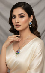 A peacock-shaped pendant necklace with blue, green, and gold enamel accents and white faux pearls, accompanied by matching earrings, displayed on a black mannequin bust. Party wear 