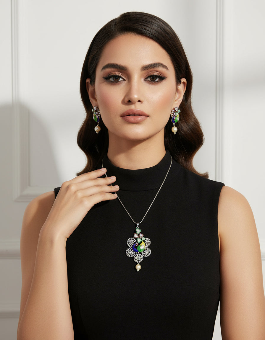 Silver polished a peacock pendant with vibrant green, blue, and gold enamel accents, along with sparkling embellishments, accompanied by matching earrings, displayed on a black mannequin necklace stand.
